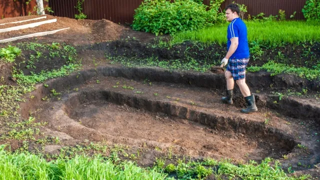 man graaft tuinvijver