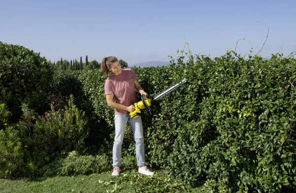 woman trimming hedge with Kärcher HGE 18-50