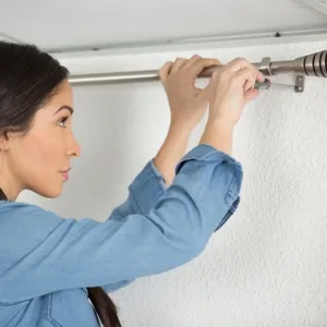 woman installs curtain rod
