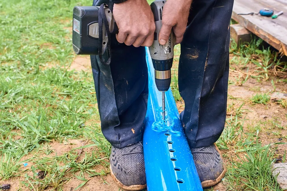 man drills into pvc pipe