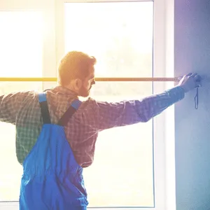 man measures window frame